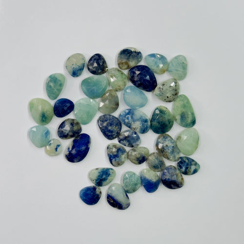 Assorted blue and green gemstones on a white background