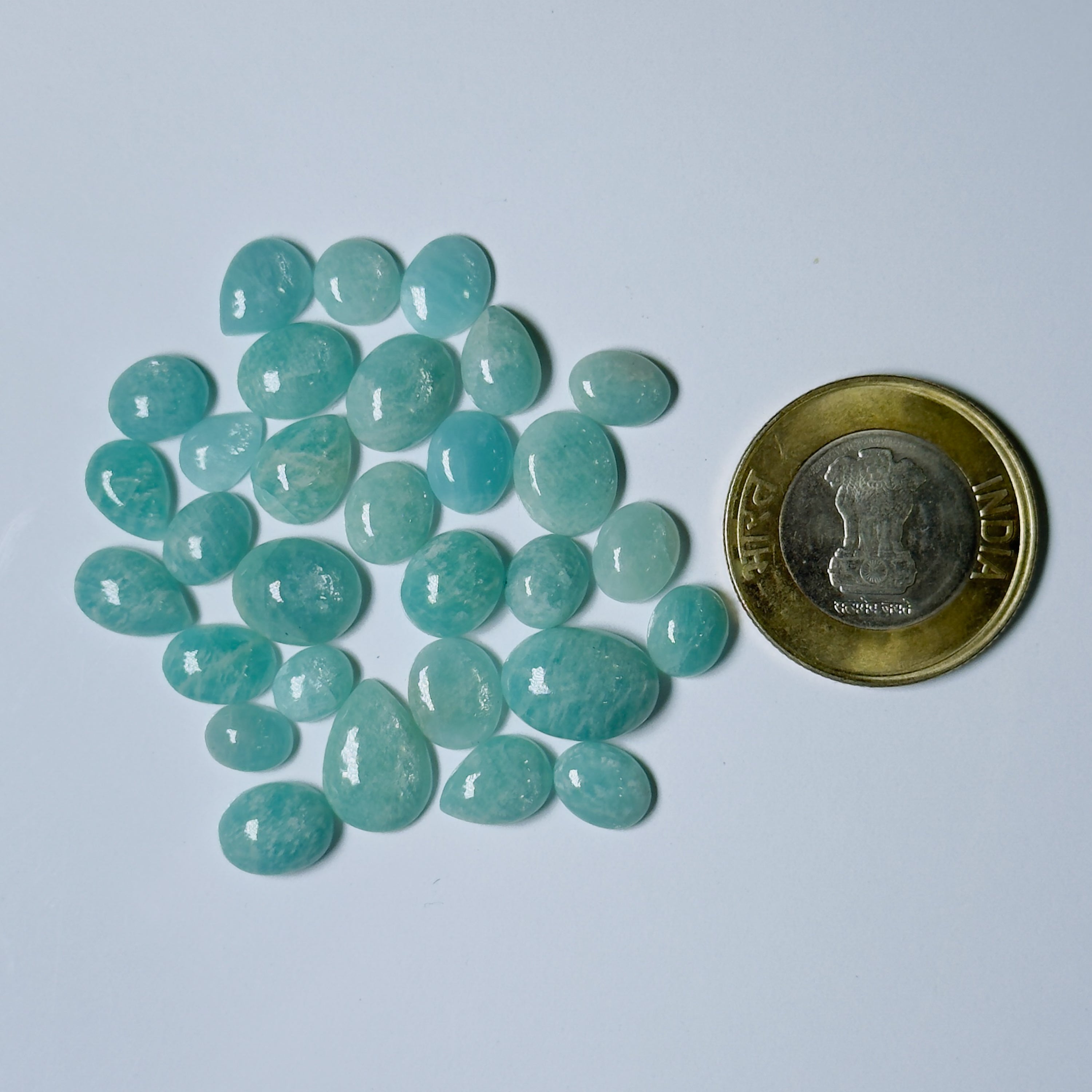Teal stones on a light gray background with a coin for scale