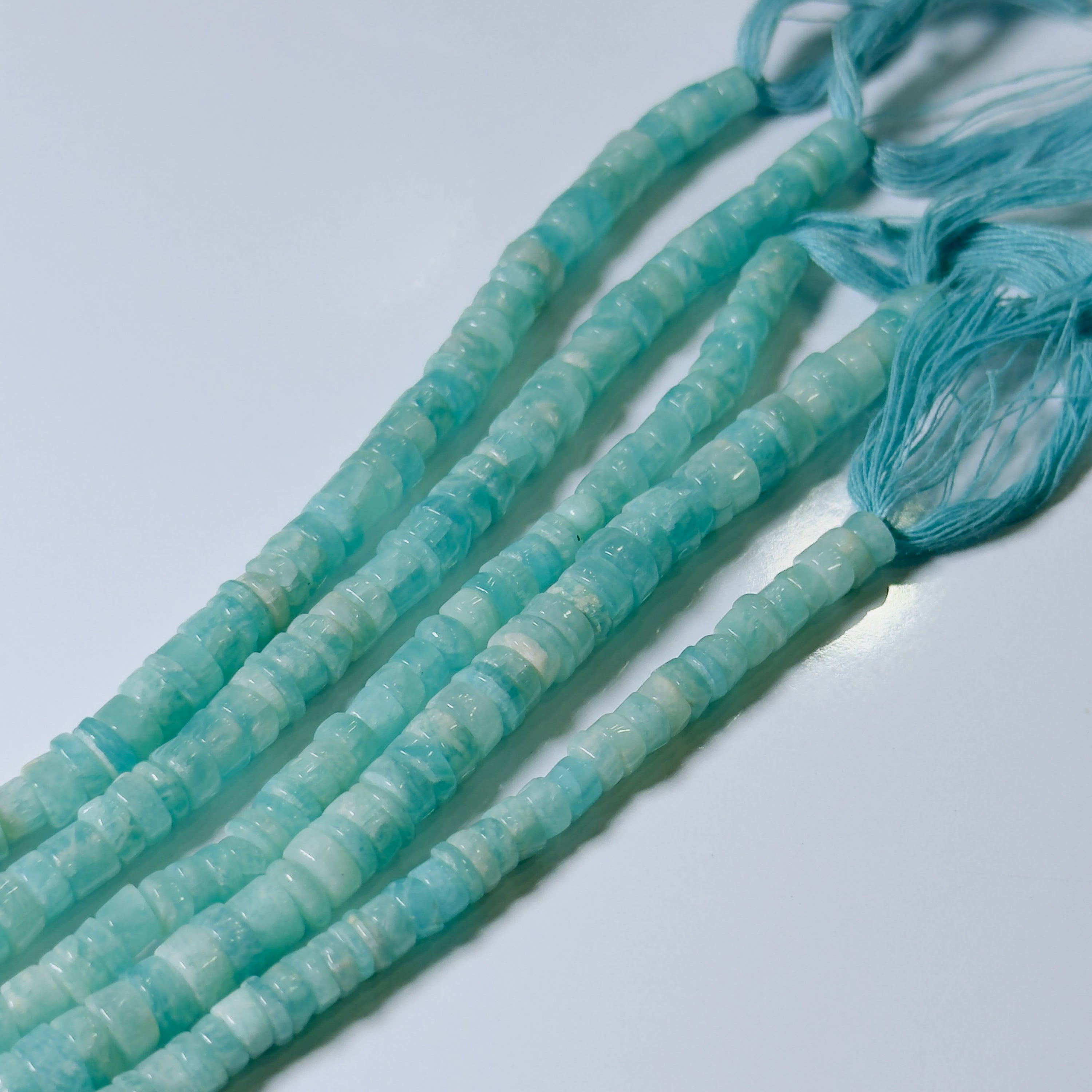 Turquoise beads on a string against a light background