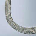 Necklace made of small, round, light-colored beads on a light gray background