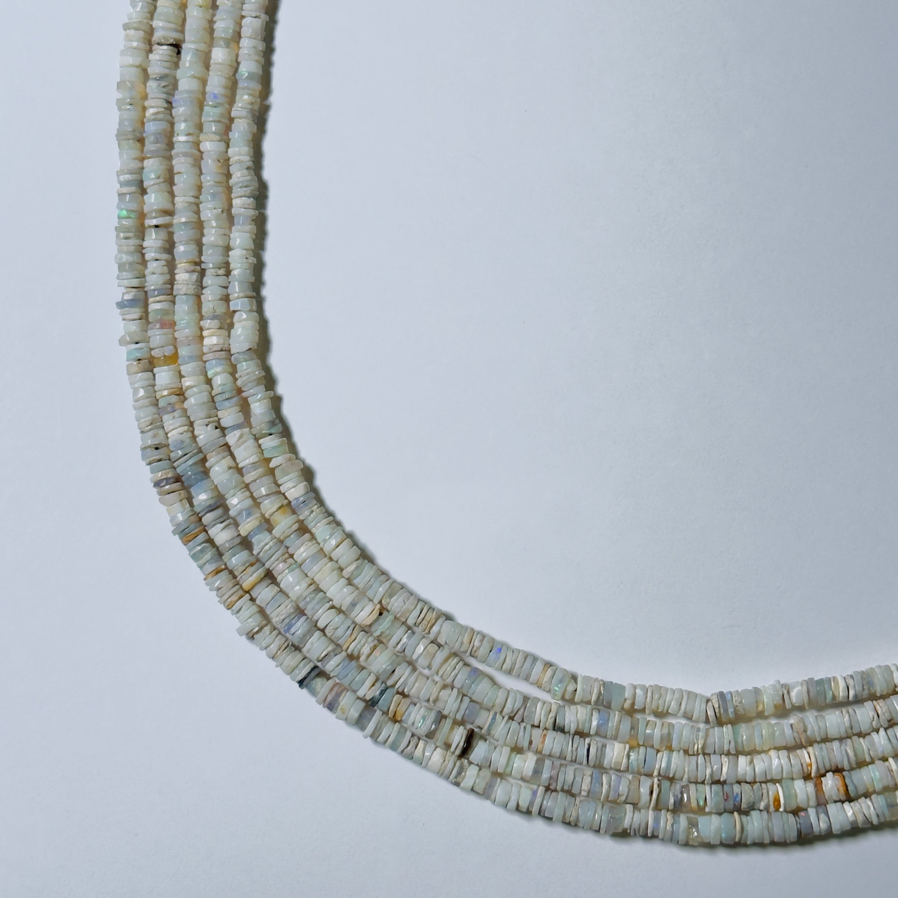 Necklace made of small, round, light-colored beads on a light gray background