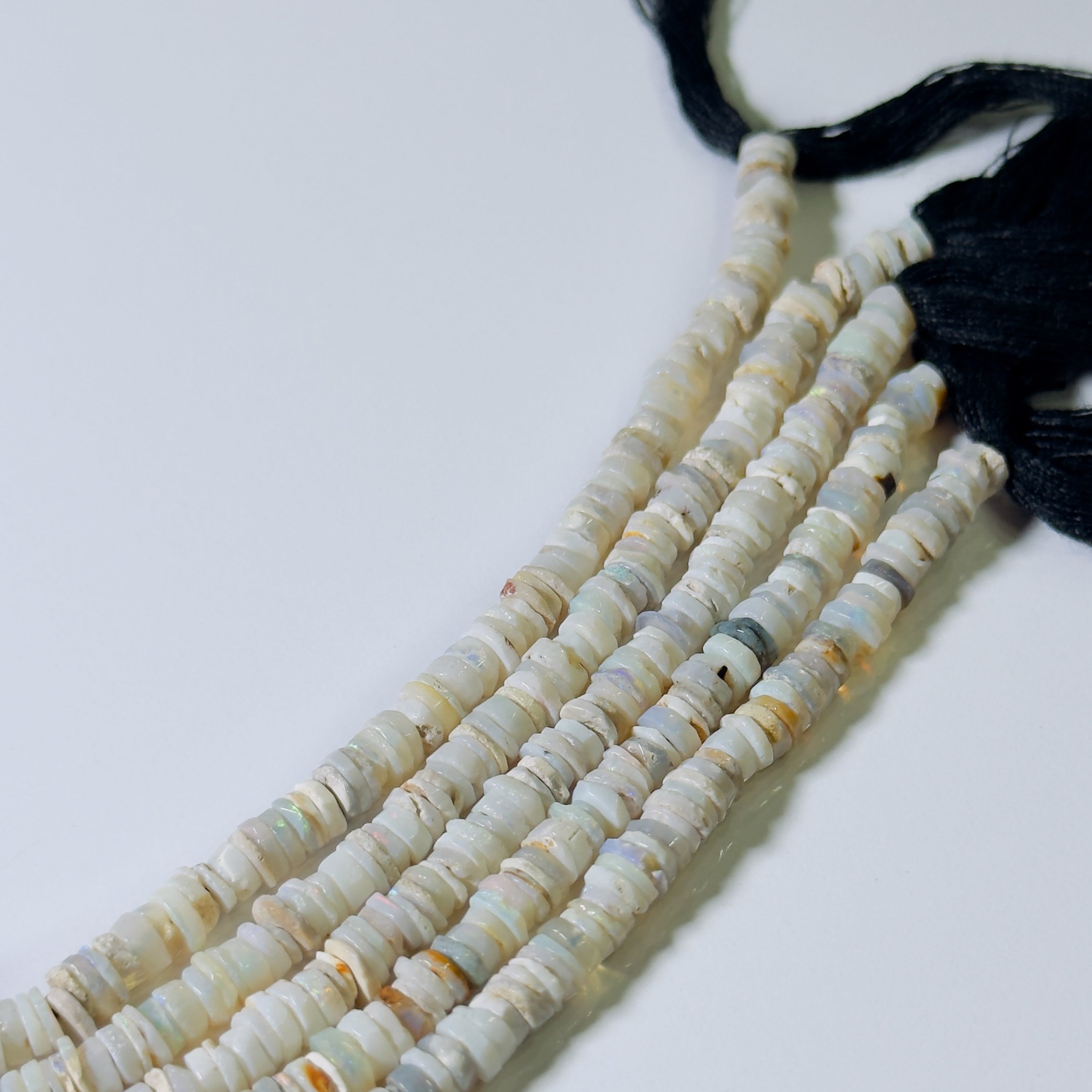String of white beads with a black tassel on a light gray background
