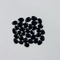 Collection of black teardrop-shaped gemstones on a light gray background