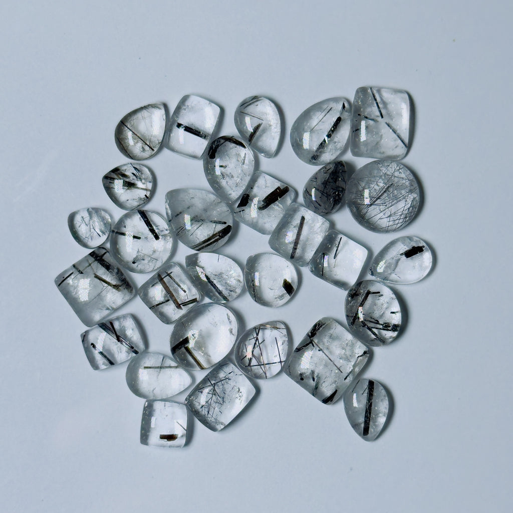 Collection of clear gemstones with black inclusions on a White background
