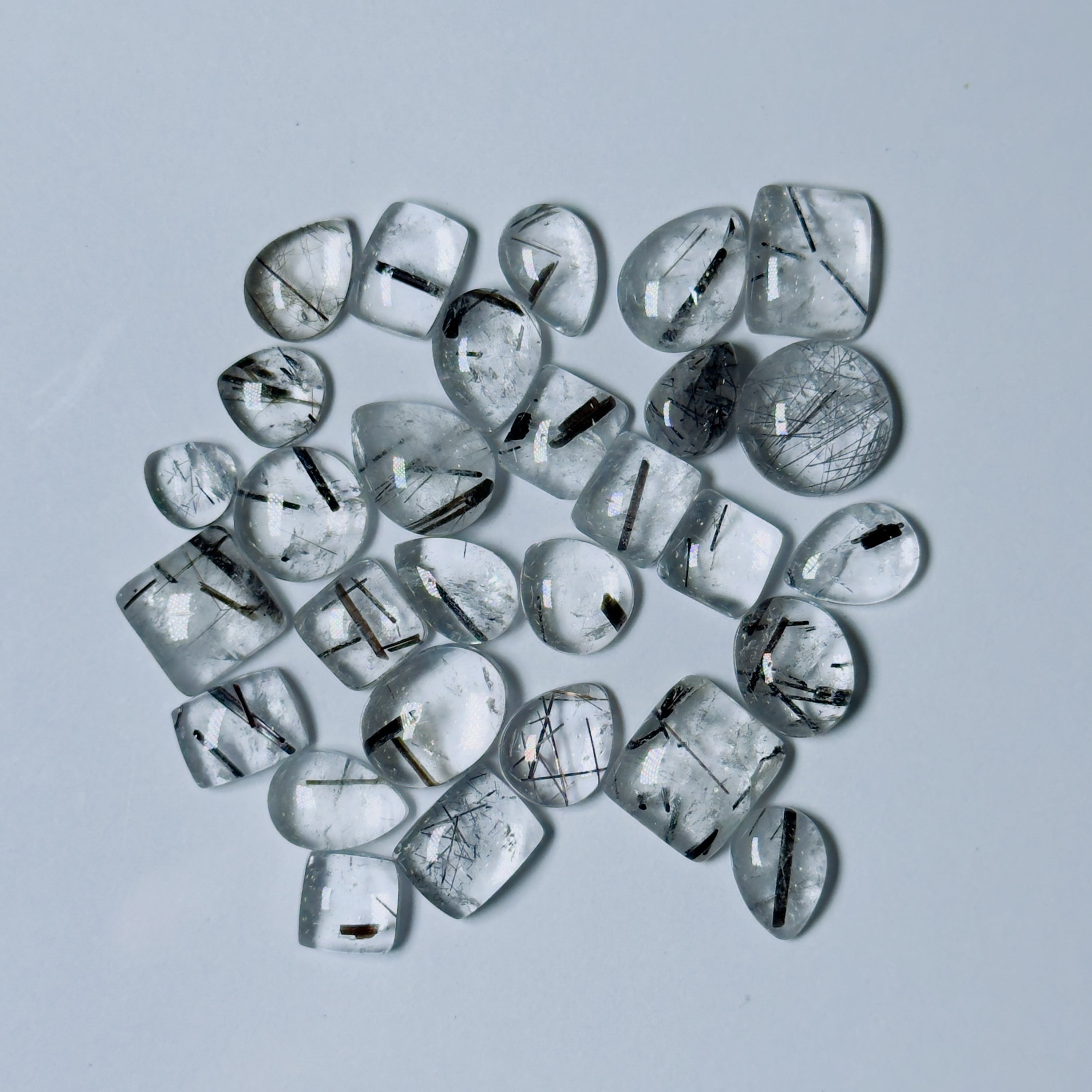 Collection of clear gemstones with black inclusions on a White background