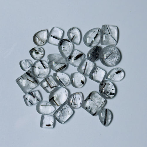 Collection of clear gemstones with black inclusions on a White background