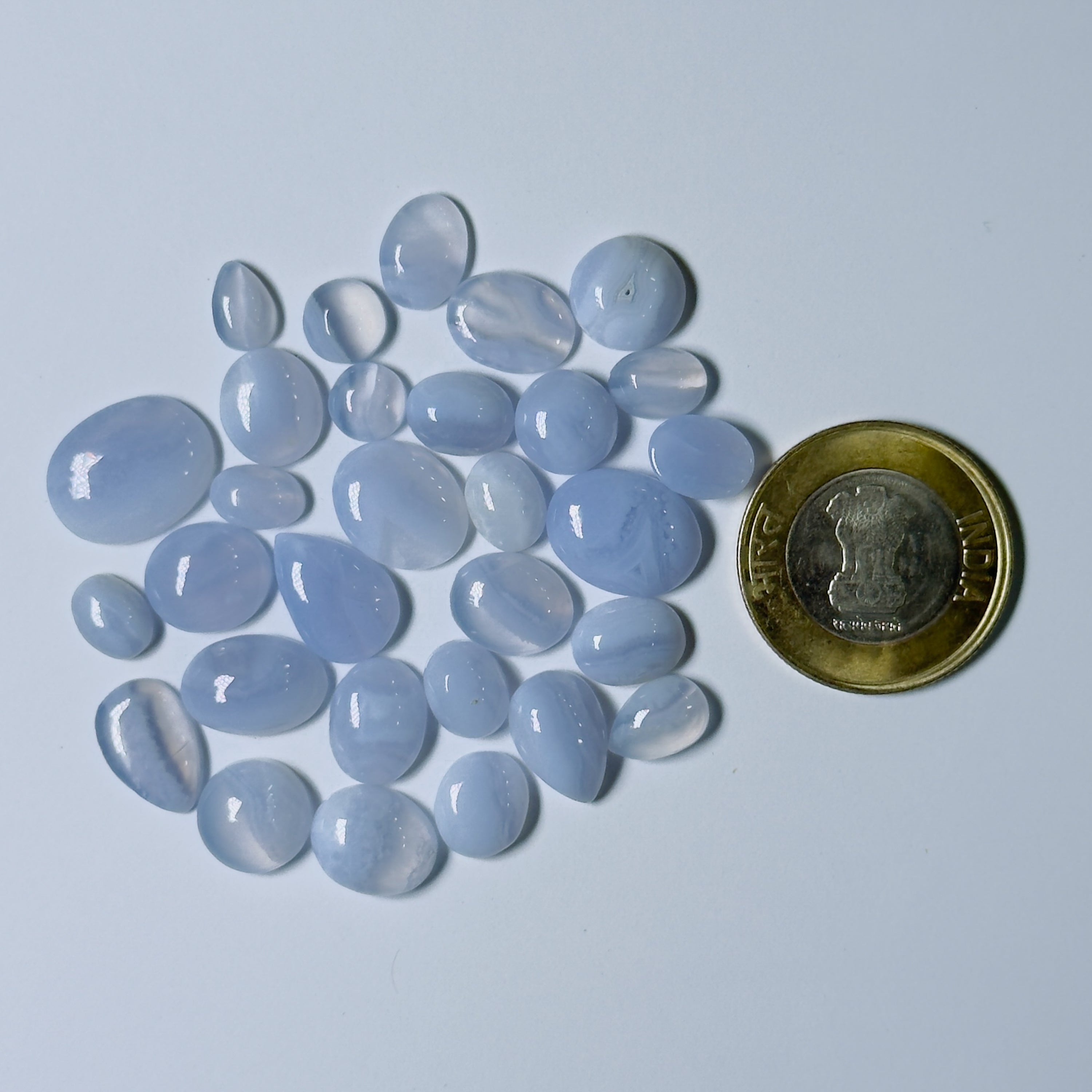 Blue chalcedony stones with a coin for scale on a light blue background