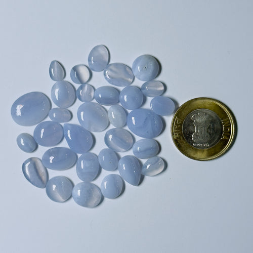 Blue chalcedony stones with a coin for scale on a light blue background