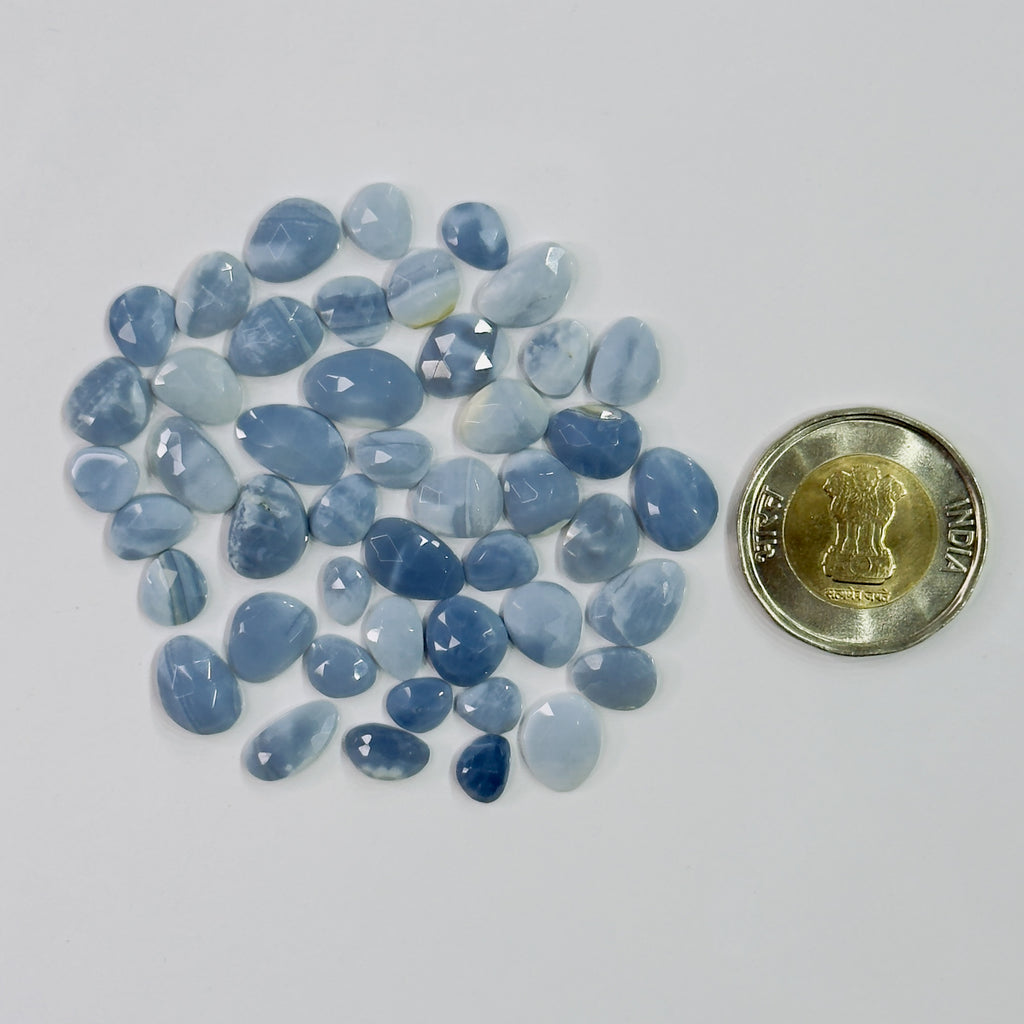 Blue gemstones with a coin for scale on a white background