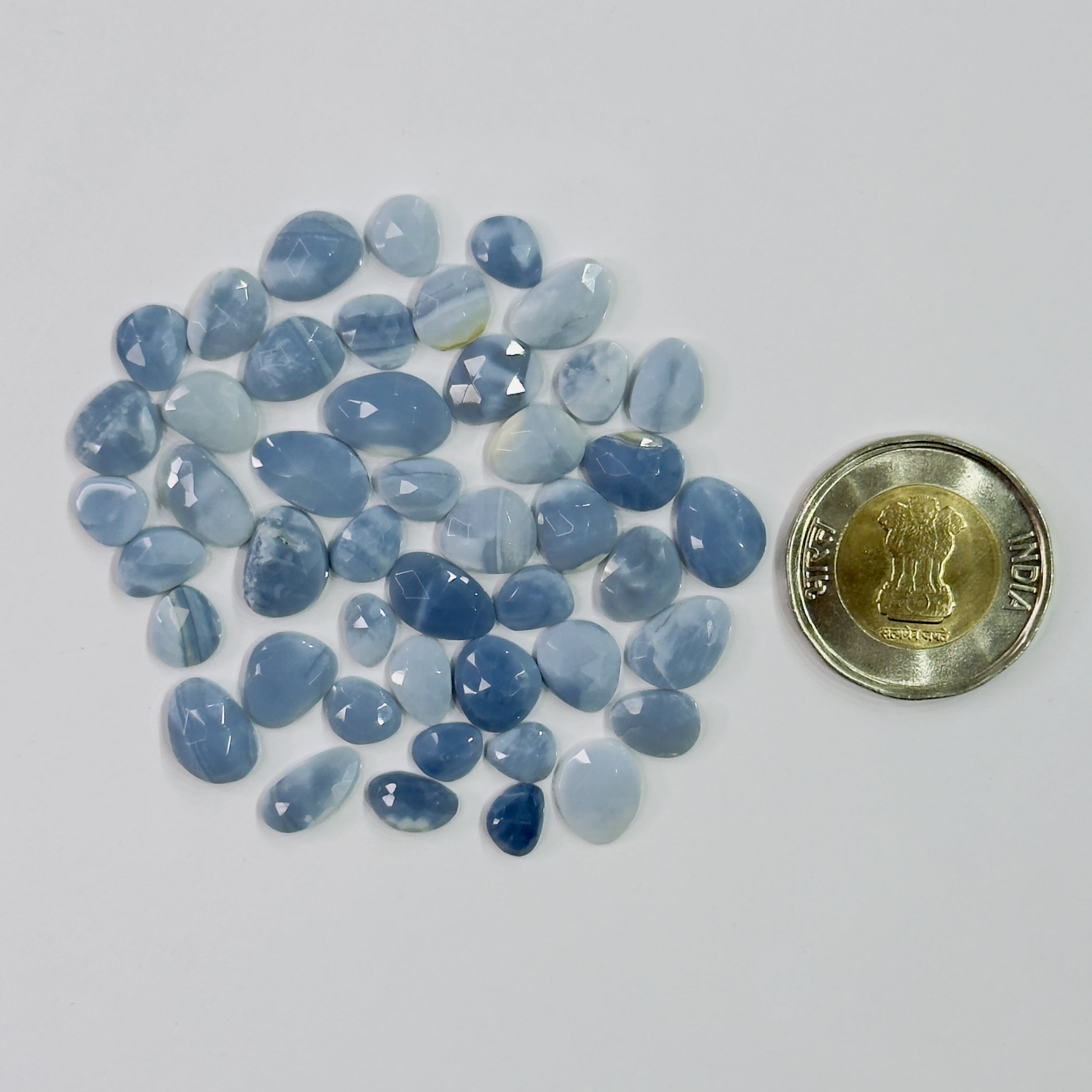 Blue gemstones with a coin for scale on a white background