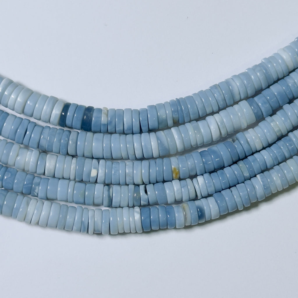 Blue heishi beads on a light gray background