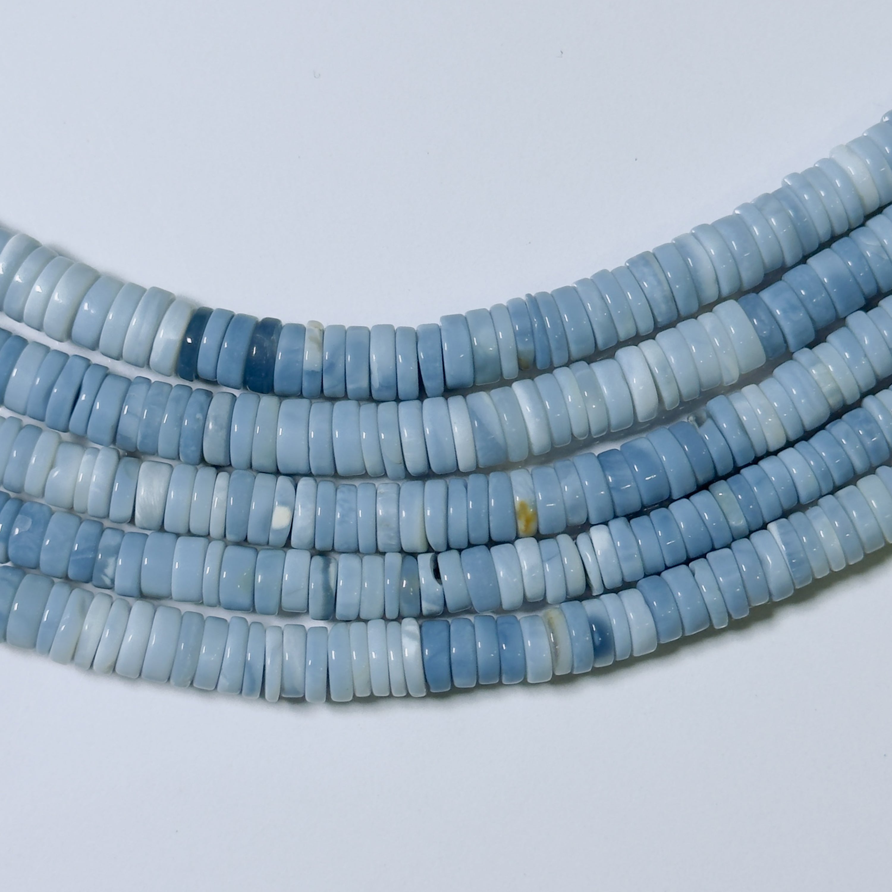 Blue heishi beads on a light gray background