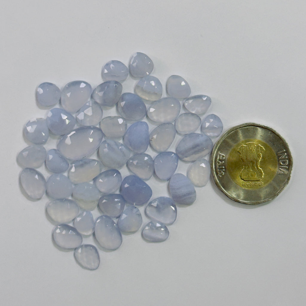 Blue chalcedony stones with a Indian rupee coin for scale on a white background