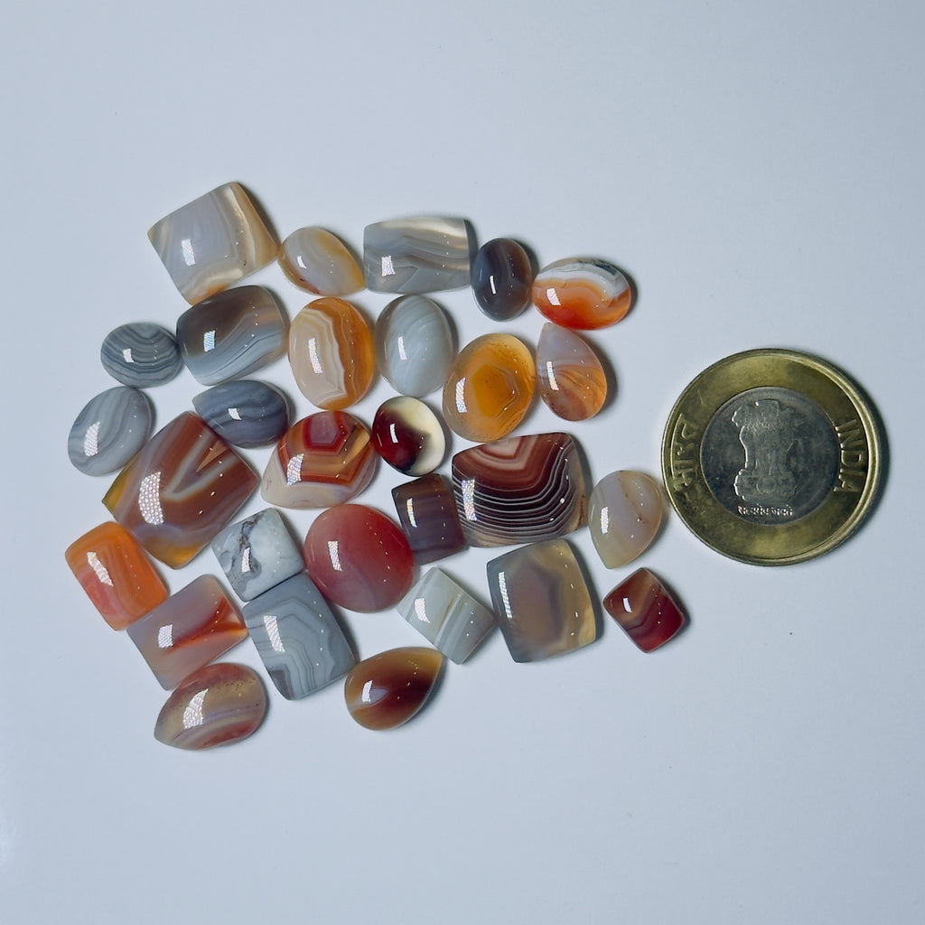 Collection of multicolored agate stones with a coin for scale on a White background