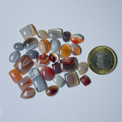 Collection of multicolored agate stones with a coin for scale on a White background
