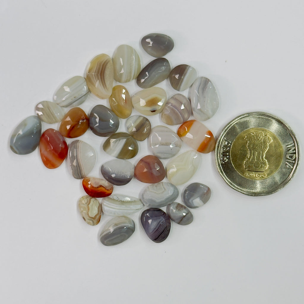 Assorted colored stones with a coin for scale on a white background
