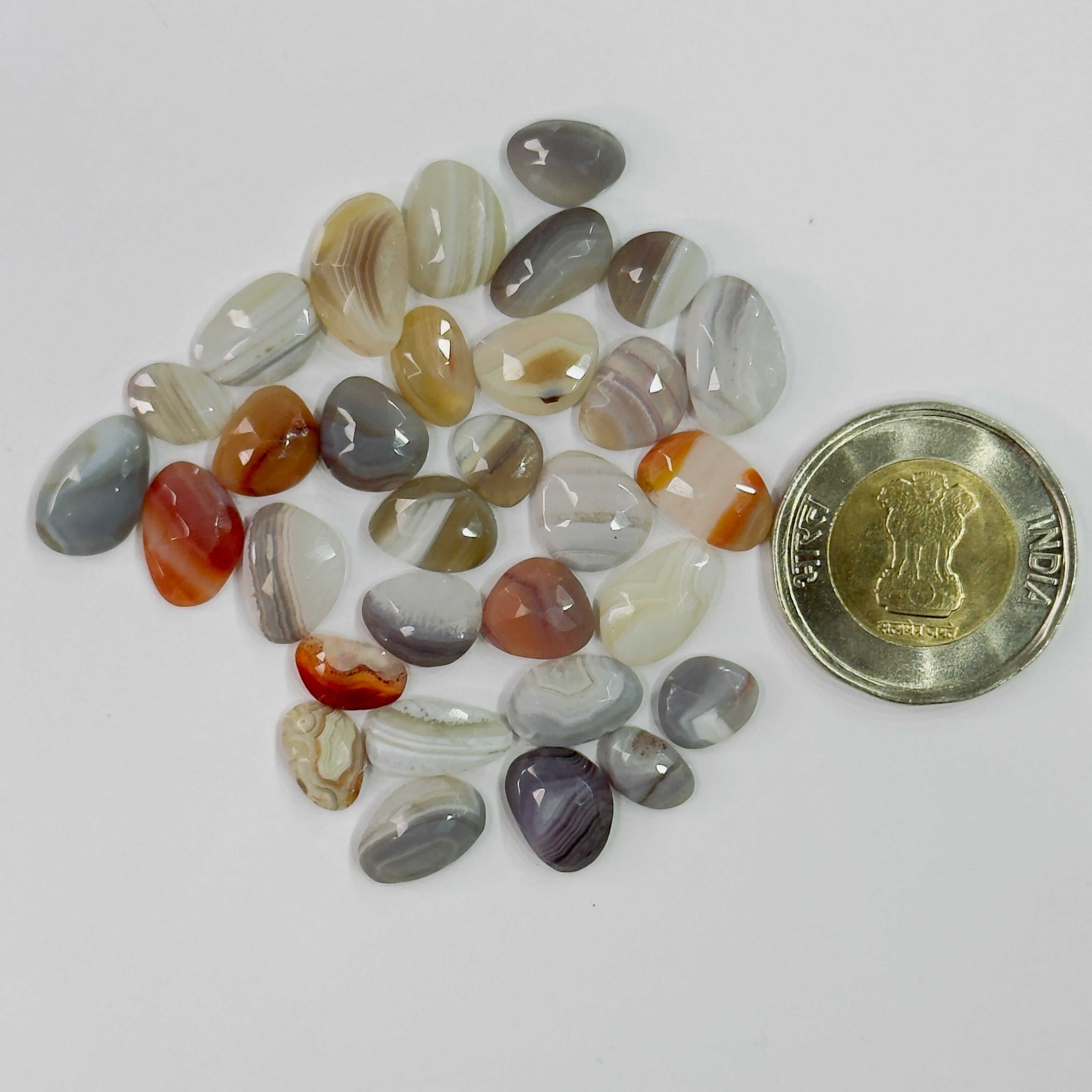 Assorted colored stones with a coin for scale on a white background