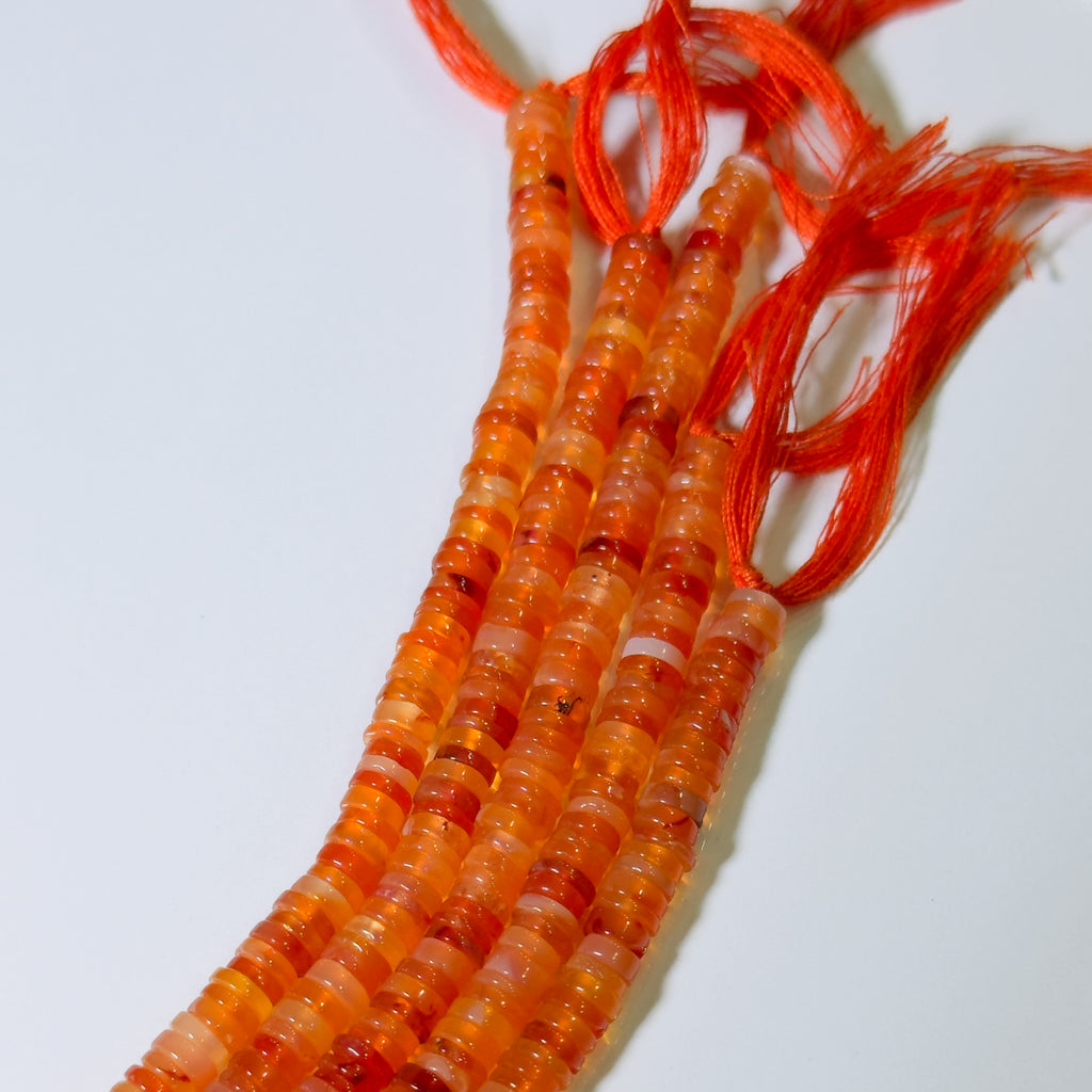 Orange beads on a red string against a white background