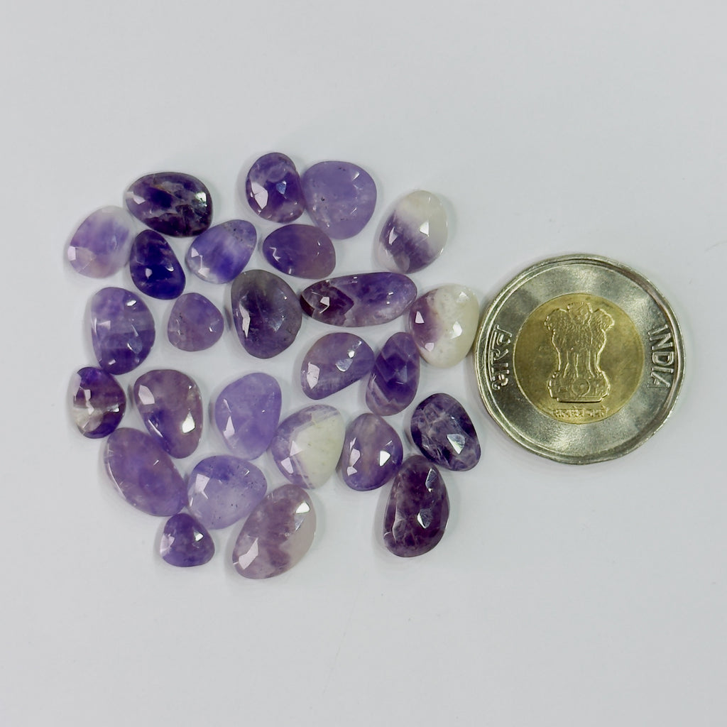 Purple gemstones with a coin for scale on a white background