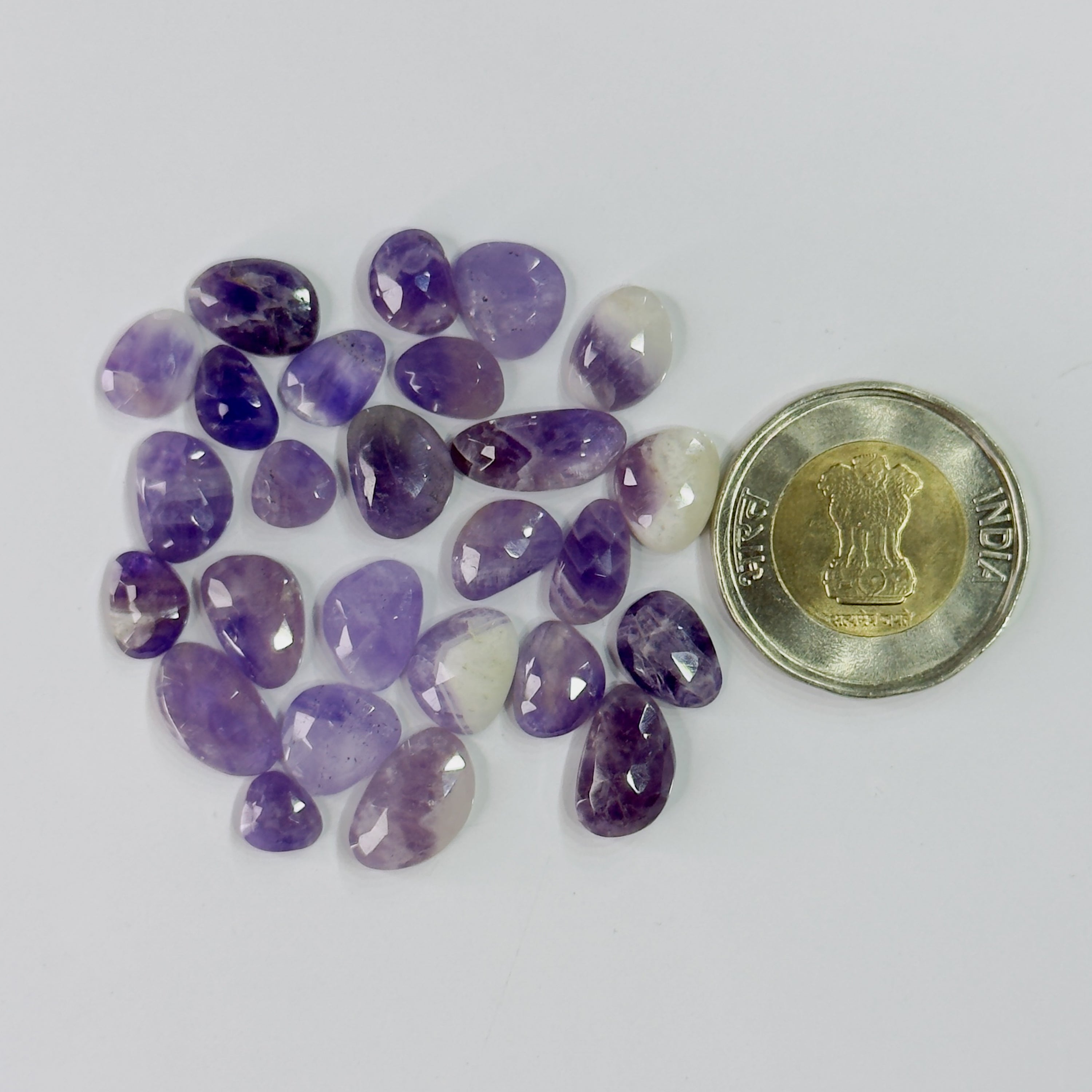 Purple gemstones with a coin for scale on a white background