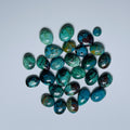 Collection of green and brown gemstones on a light gray background