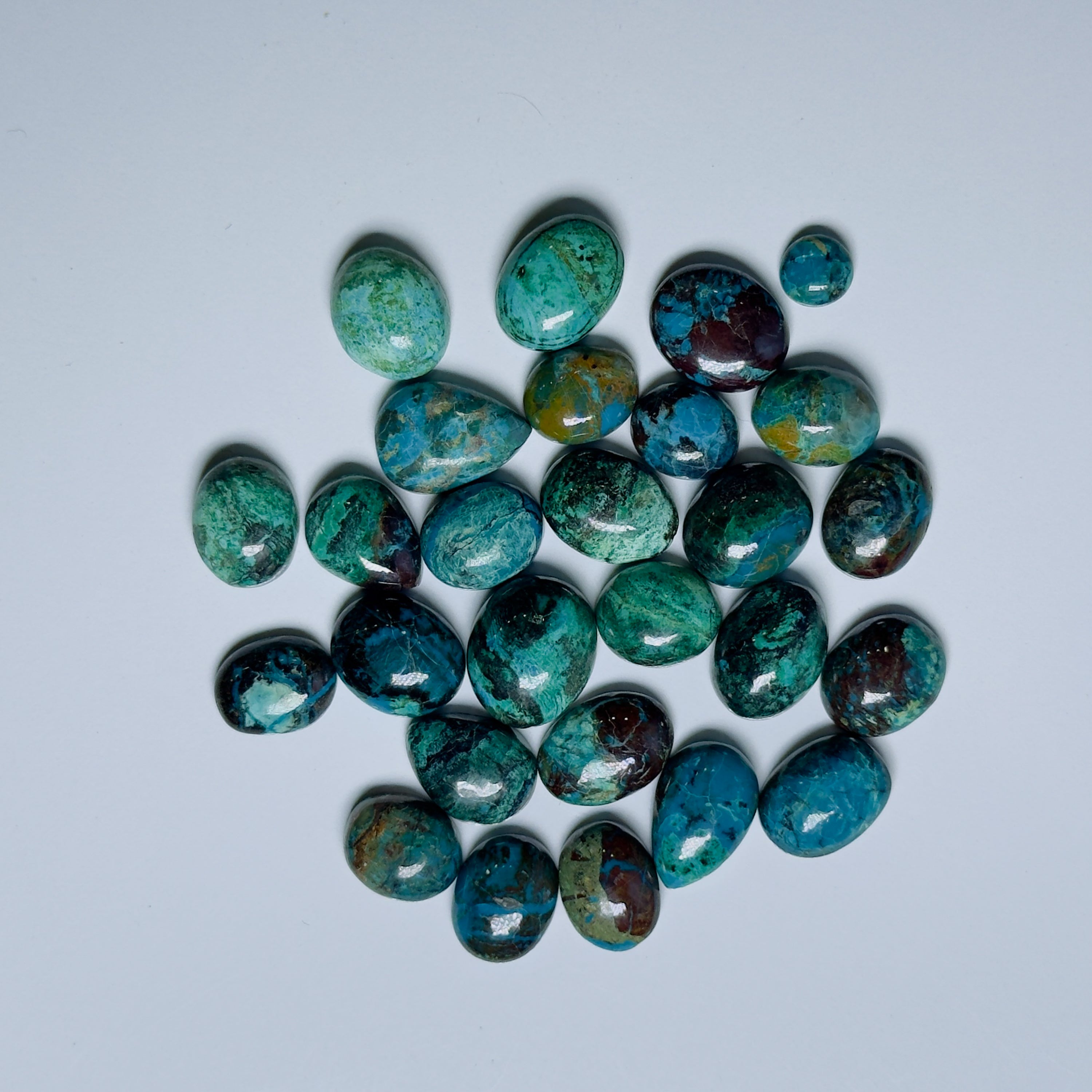 Collection of green and brown gemstones on a light gray background