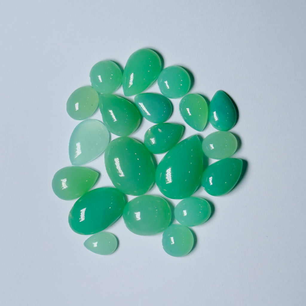 Green teardrop-shaped gemstones on a light gray background