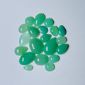 Green teardrop-shaped gemstones on a light gray background