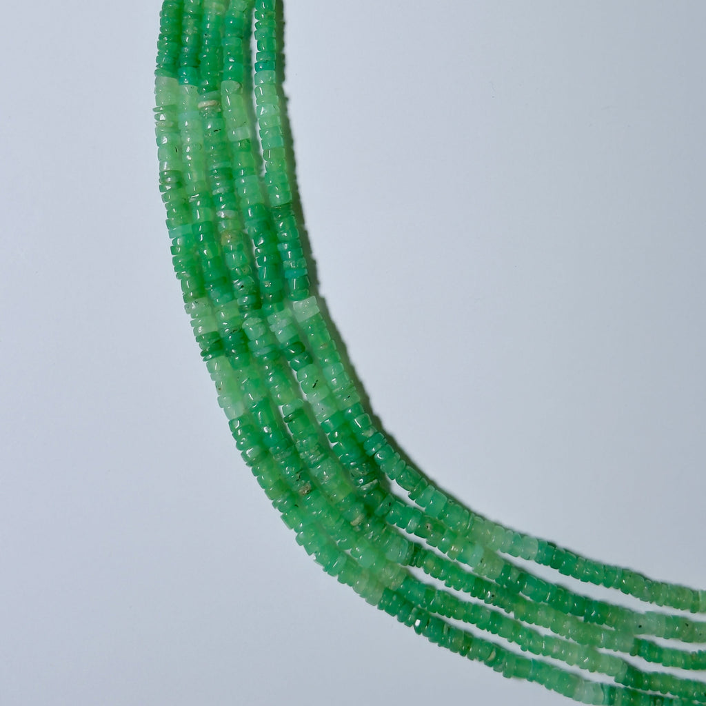 Close-up of green bead necklace on a light gray background