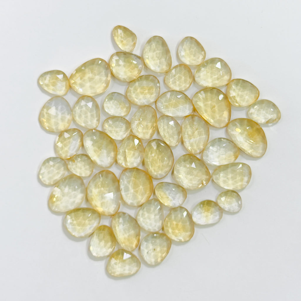 Collection of yellow teardrop-shaped gemstones on a light gray background