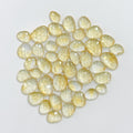 Collection of yellow teardrop-shaped gemstones on a light gray background