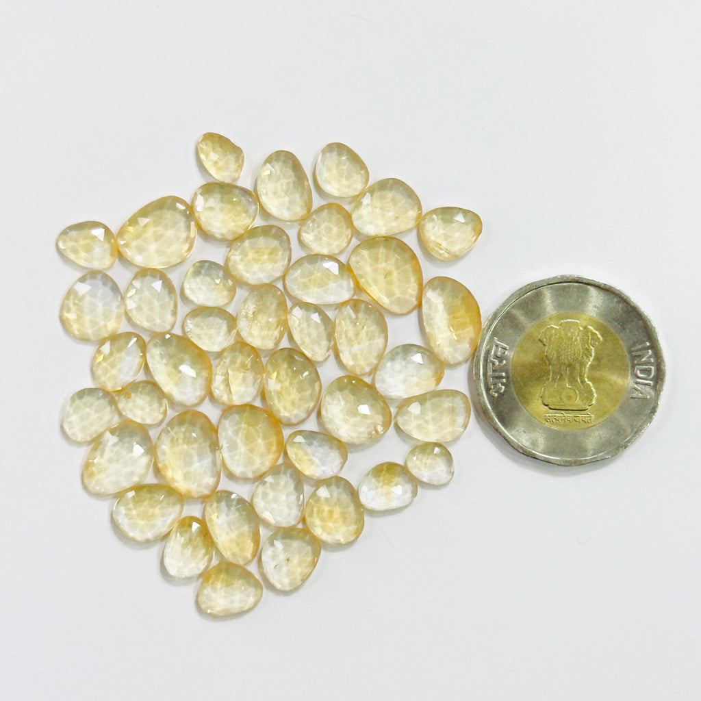 Yellow gemstones with a coin for scale on a white background