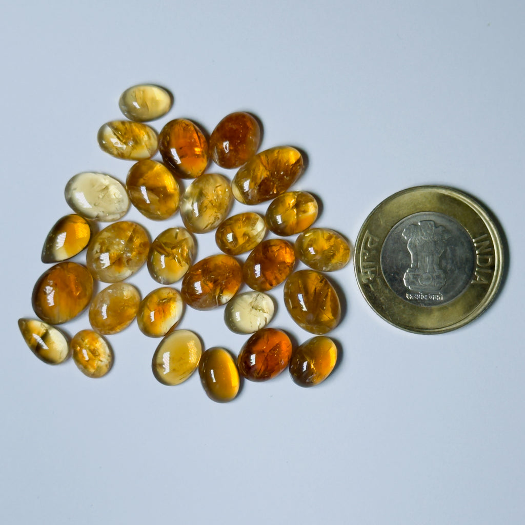 Collection of amber stones with a coin for scale on a Whitebackground