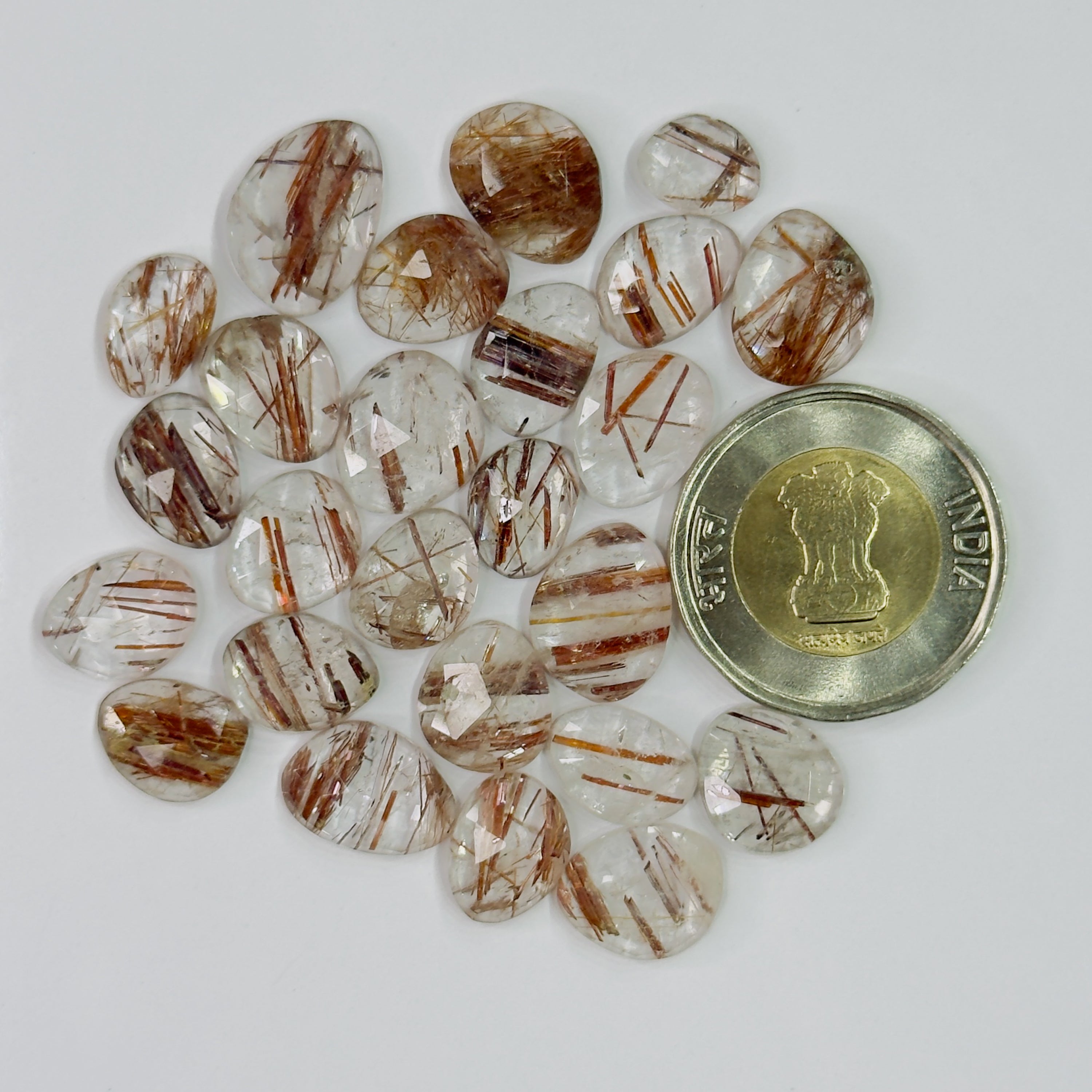 Collection of brown and clear stones with a coin for scale on a white background