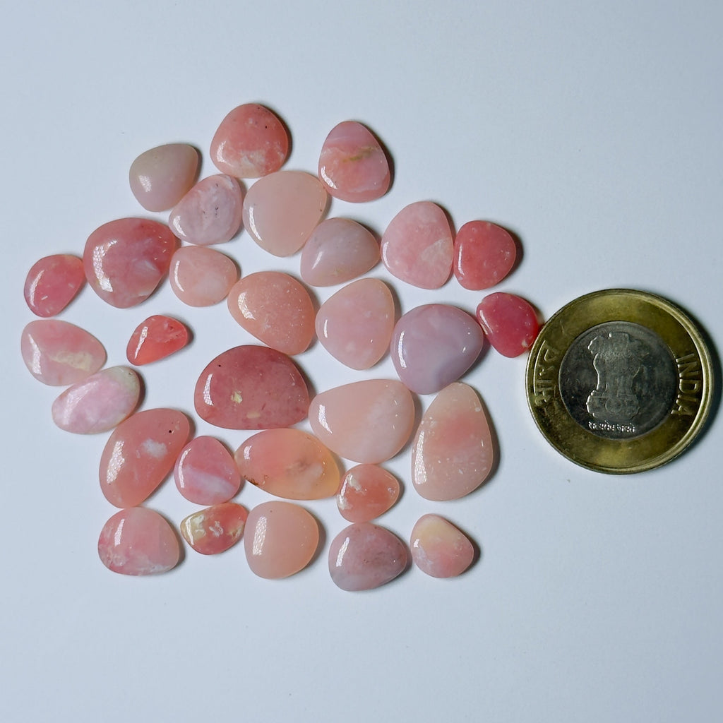 Pink stones with a coin for scale on a white background