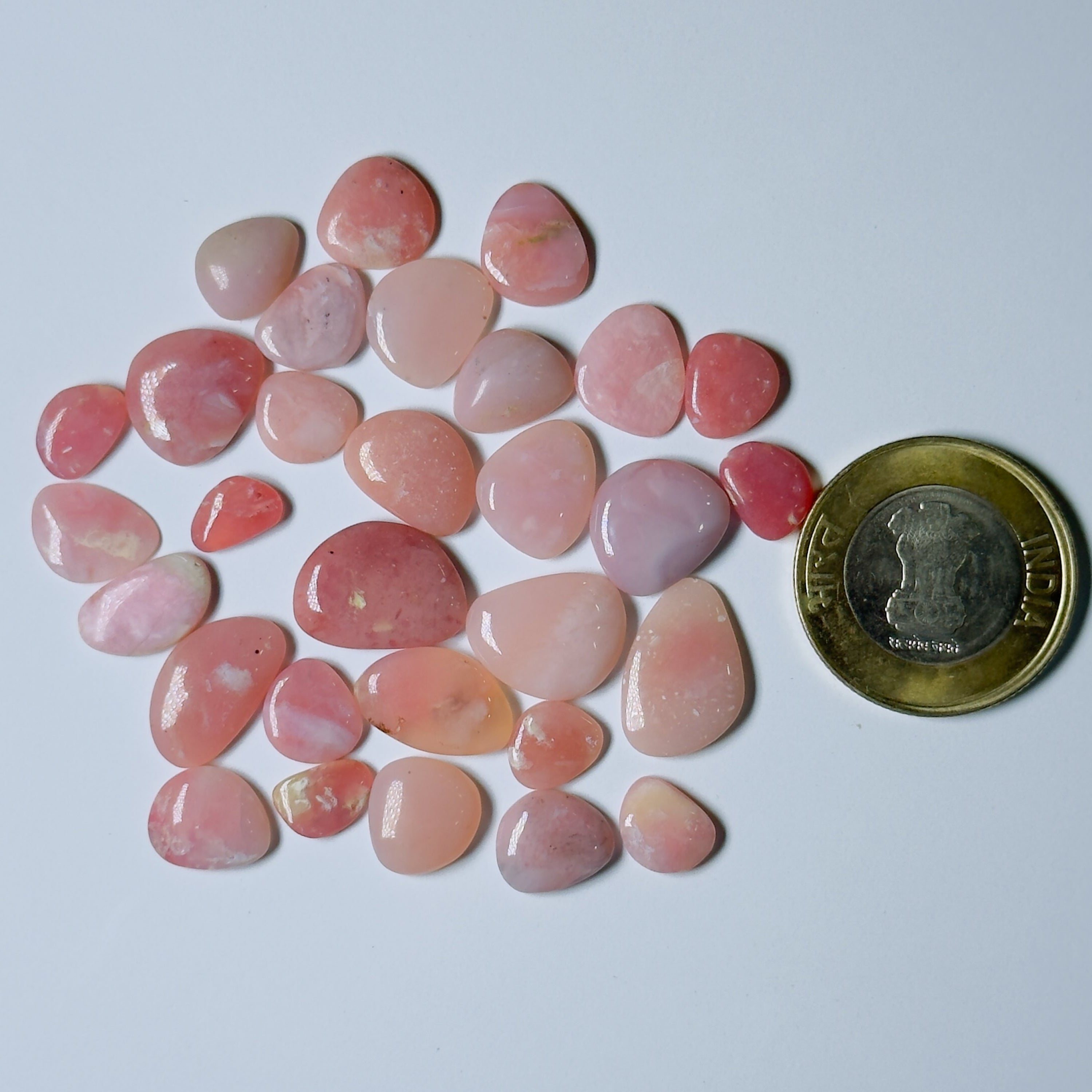 Pink stones with a coin for scale on a white background