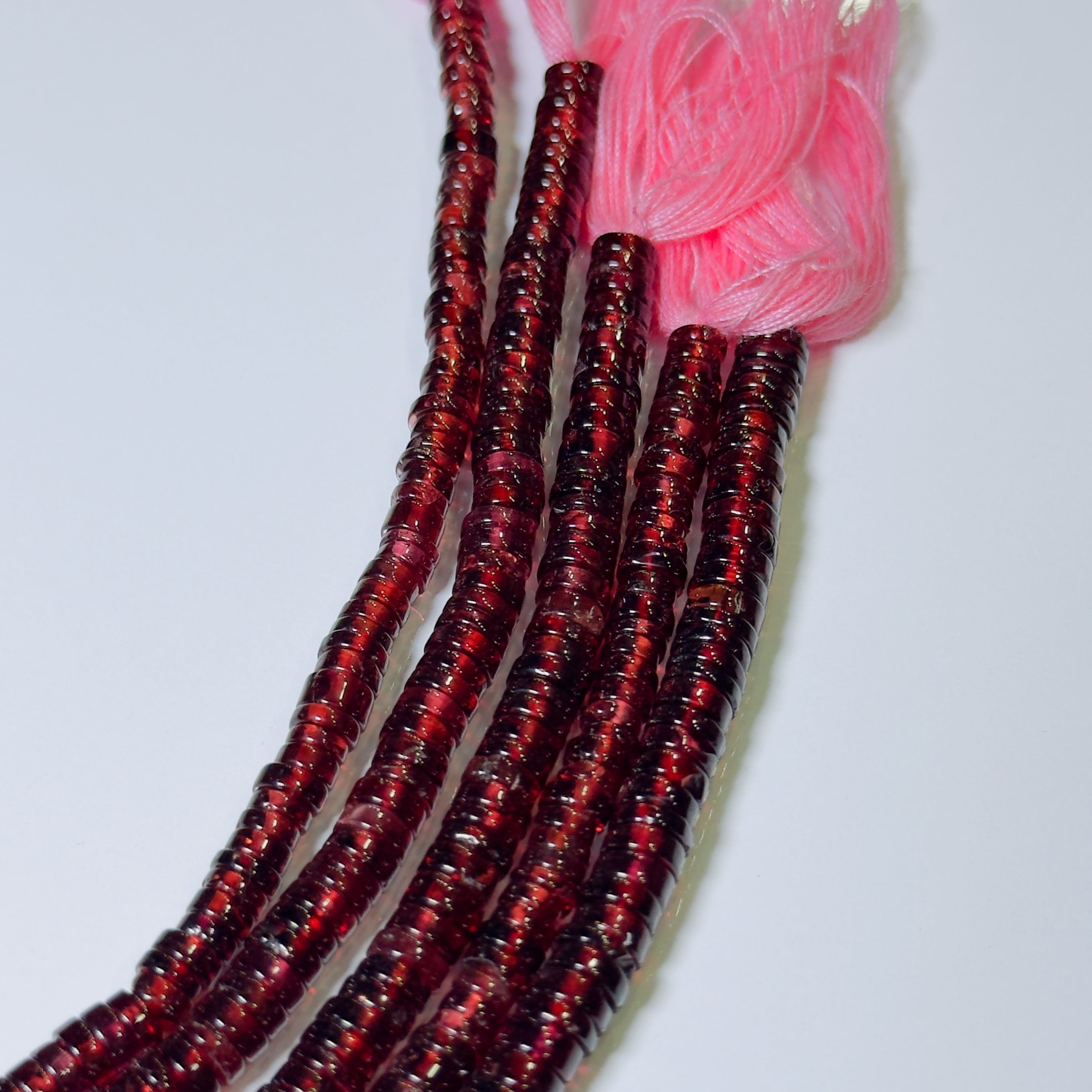 Red beaded hair extensions with a pink section on a white background