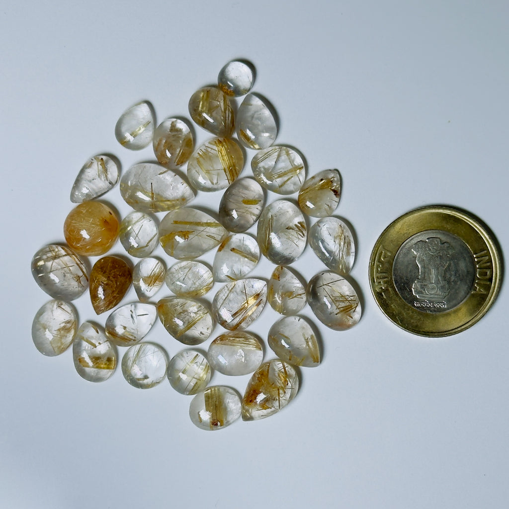 Teardrop-shaped gemstones with a coin for scale on a White background