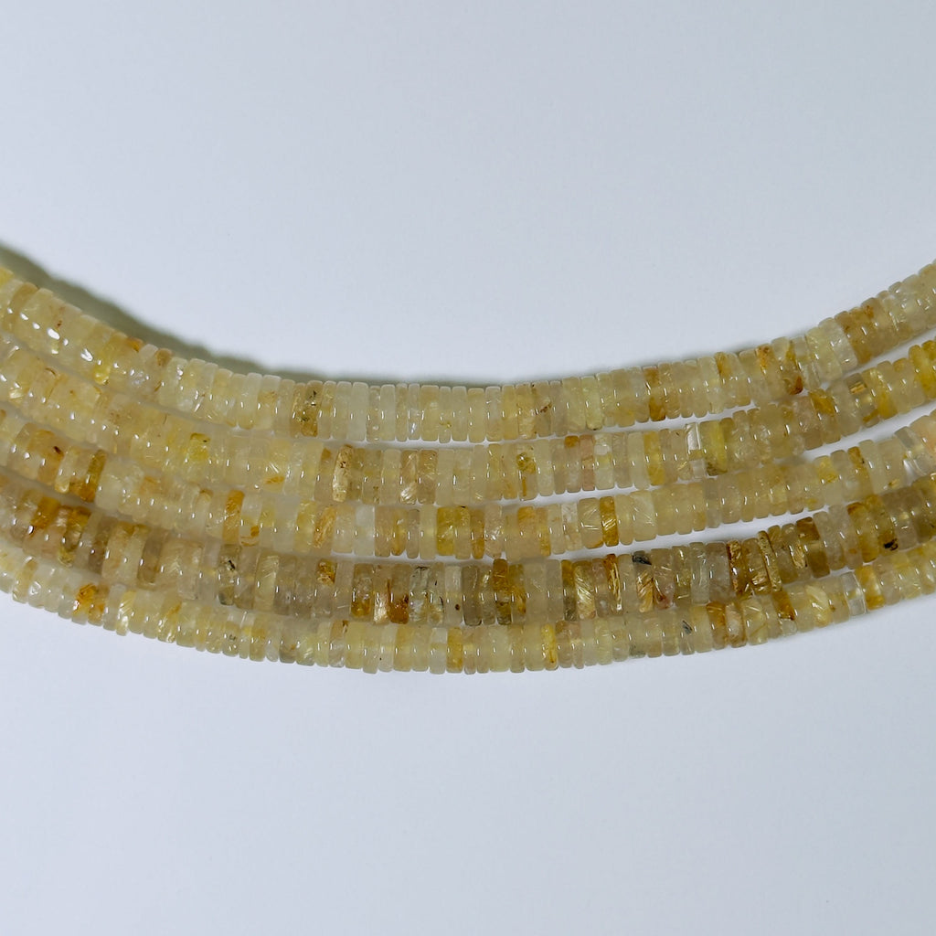 Close-up of a string of small yellow beads on a white background
