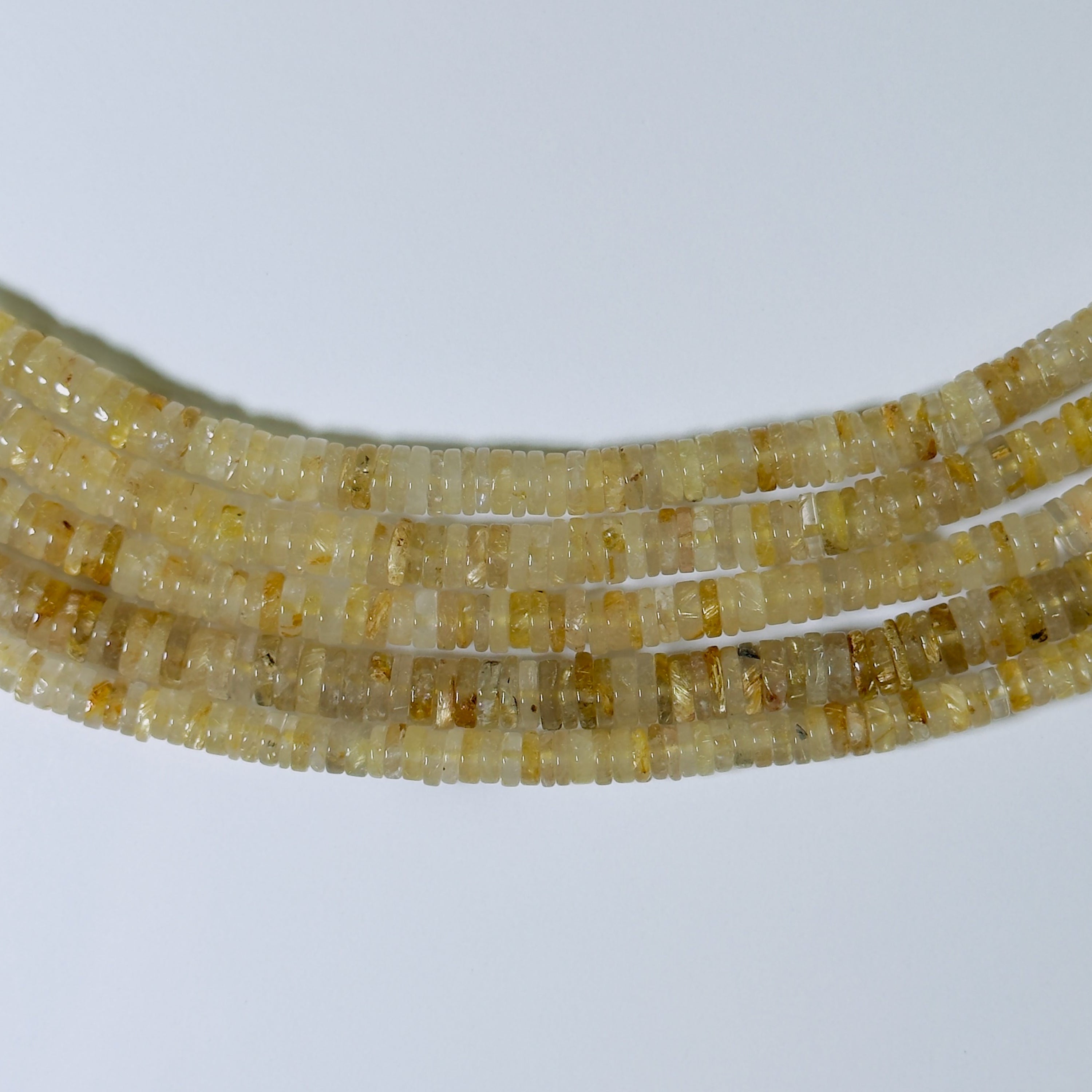Close-up of a string of small yellow beads on a white background