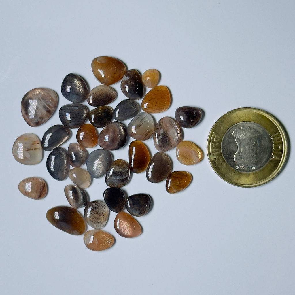 Collection of small, multicolored stones with a coin for scale on a light gray background