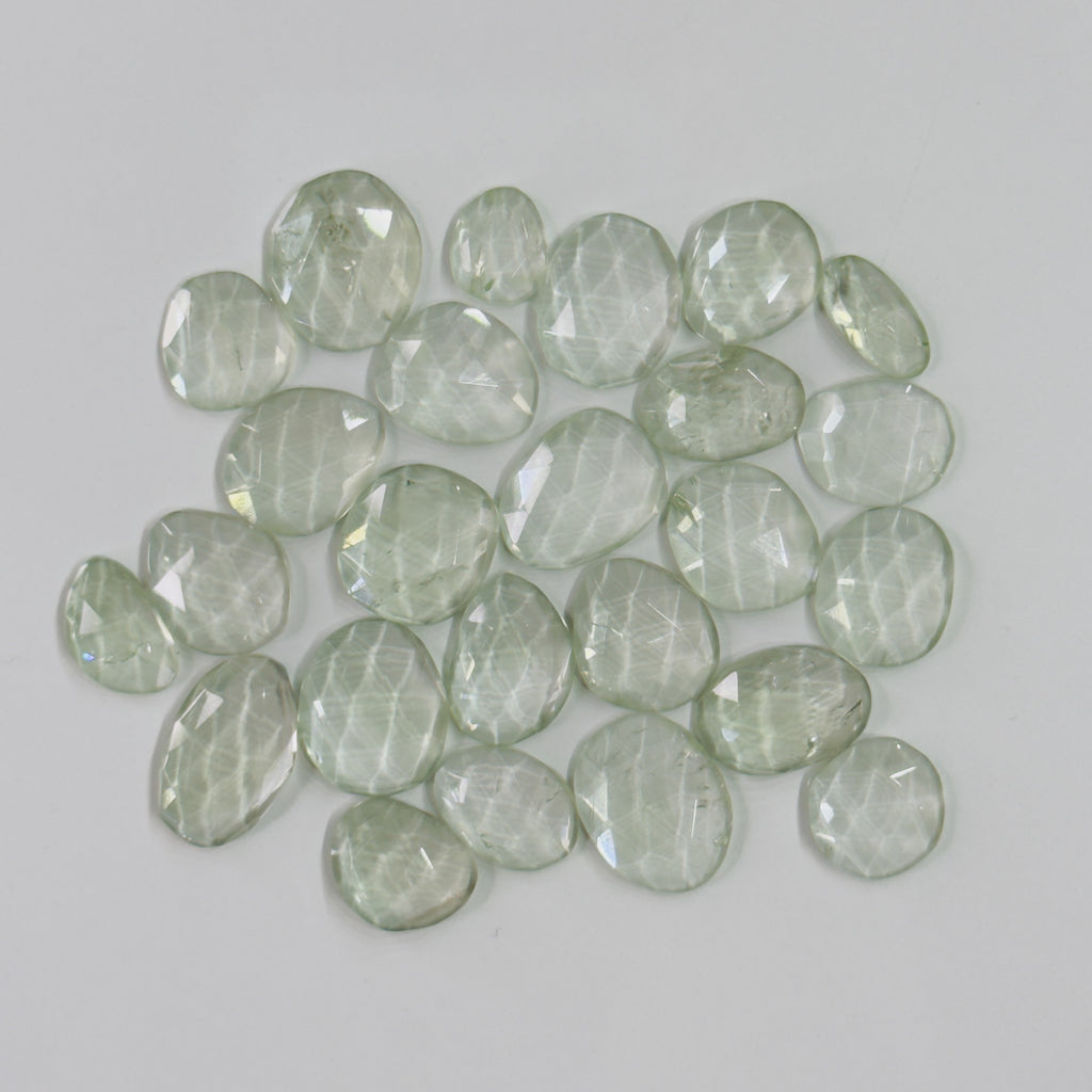 Collection of green faceted stones on a light gray background