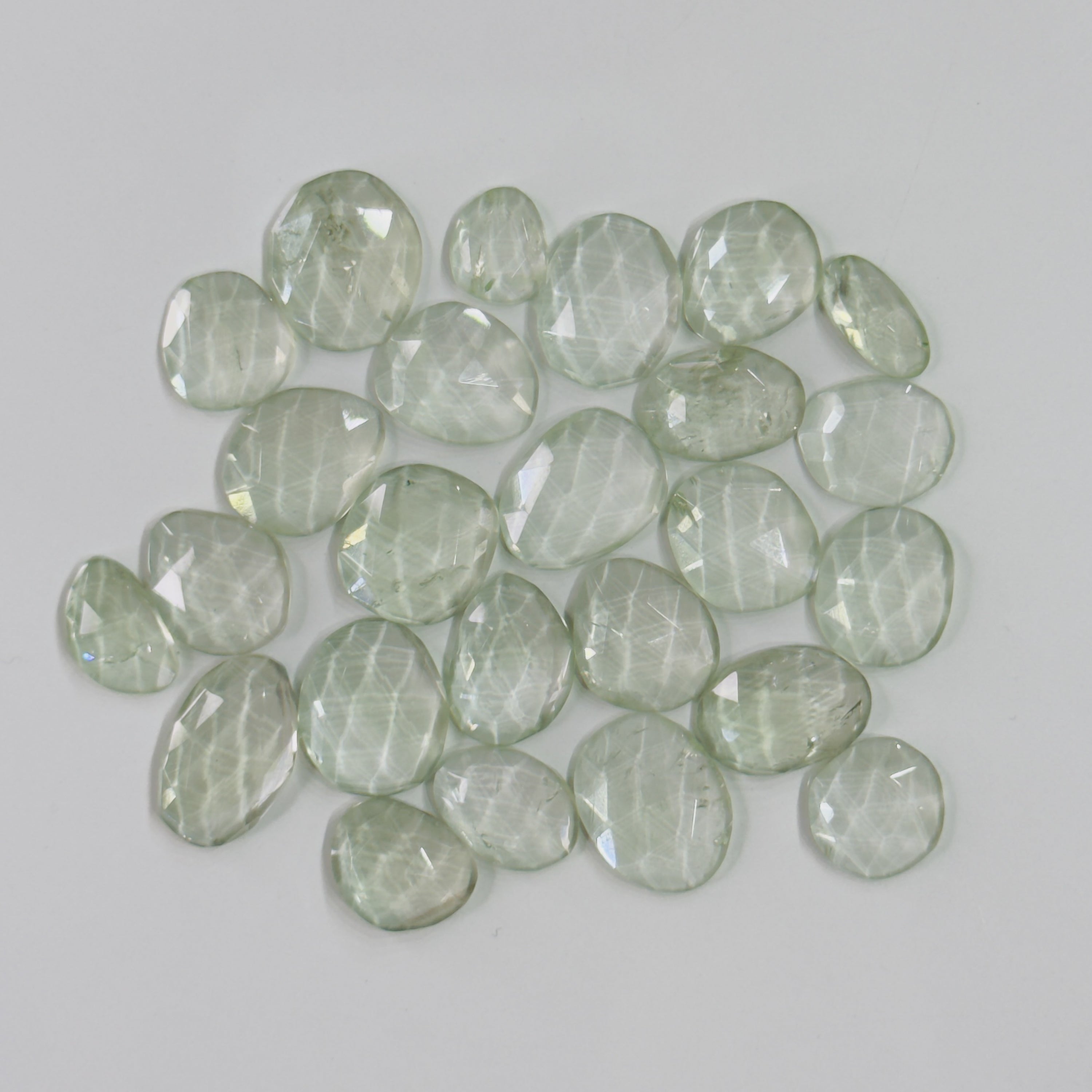 Collection of green faceted stones on a light gray background