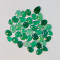 Collection of green teardrop-shaped gemstones on a light gray background
