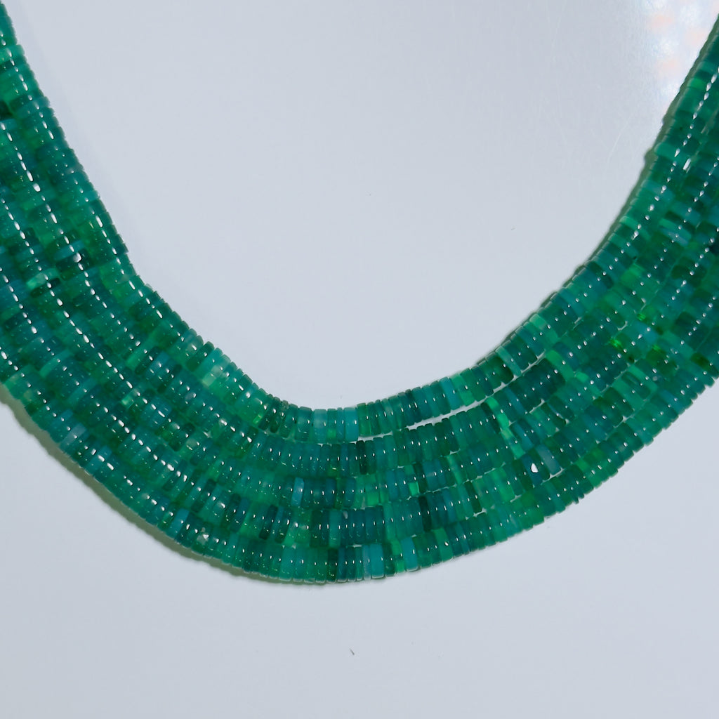 Close-up of a green beaded necklace on a light gray background