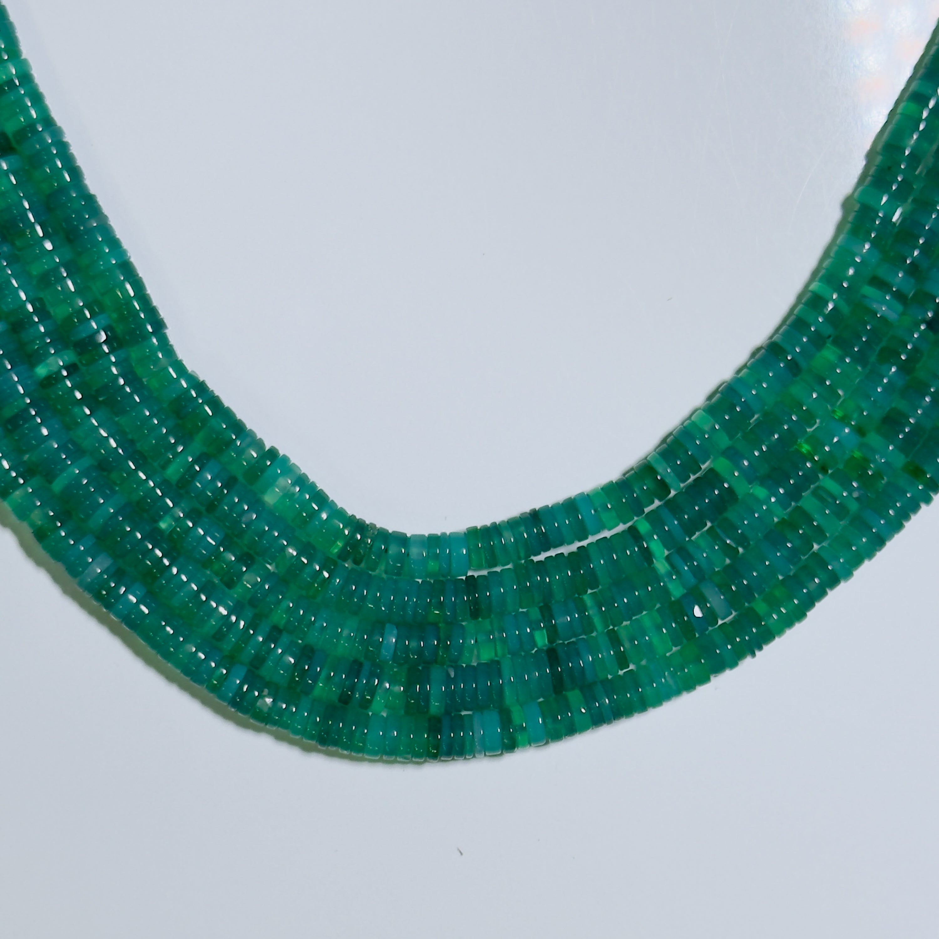 Close-up of a green beaded necklace on a light gray background