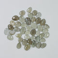 Collection of greenish-brown teardrop-shaped stones on a light gray background