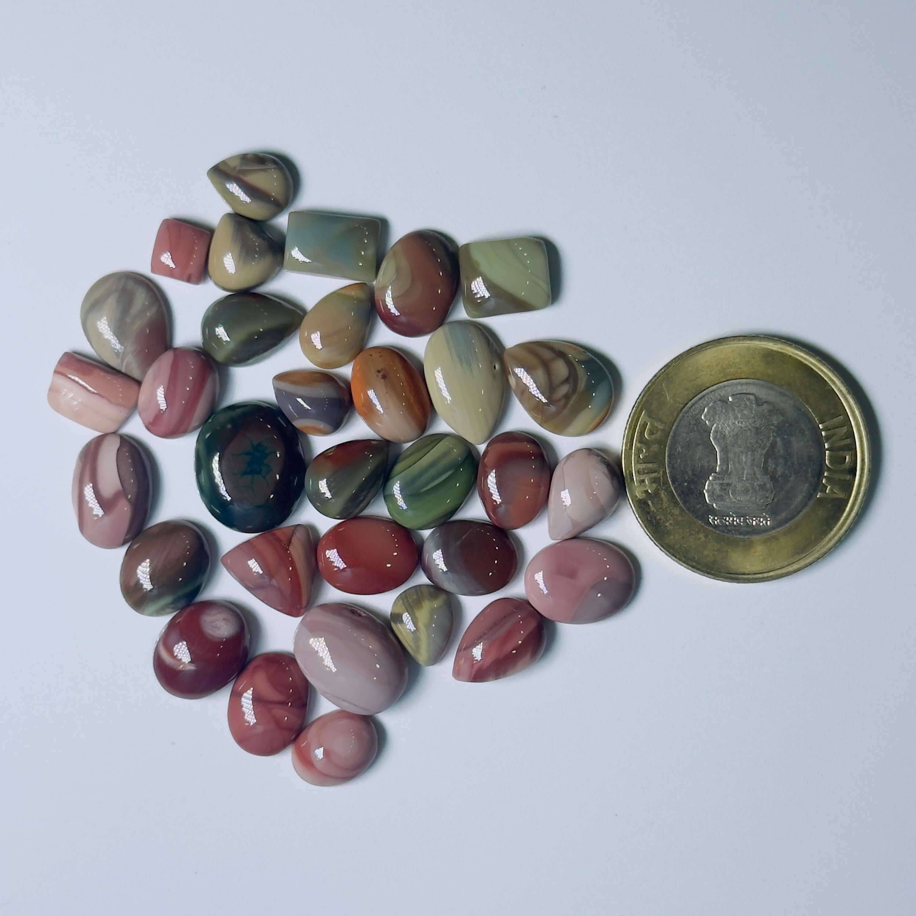 Collection of multicolored stones with a coin for scale on a lWhite background