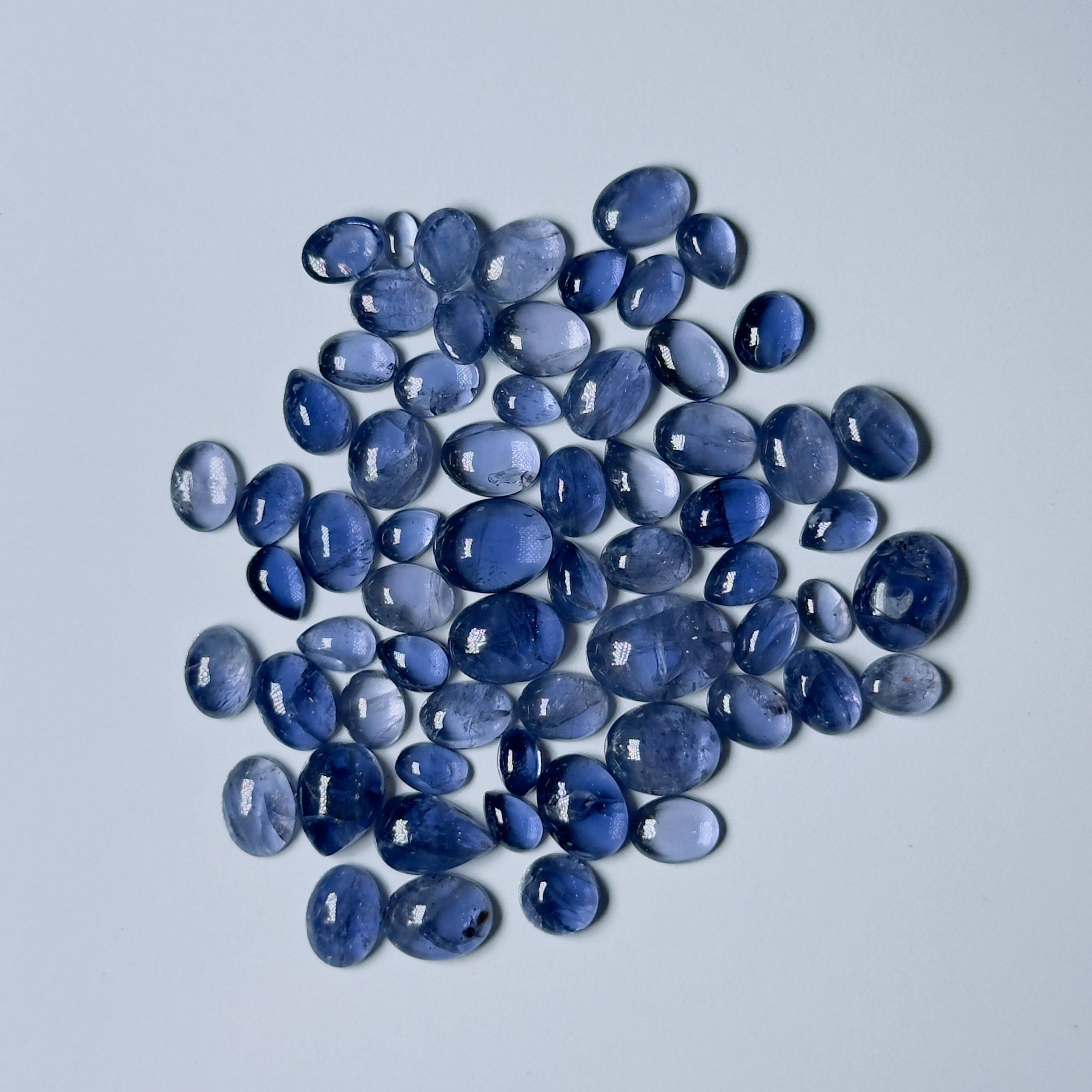 Collection of blue teardrop-shaped stones on a light gray background