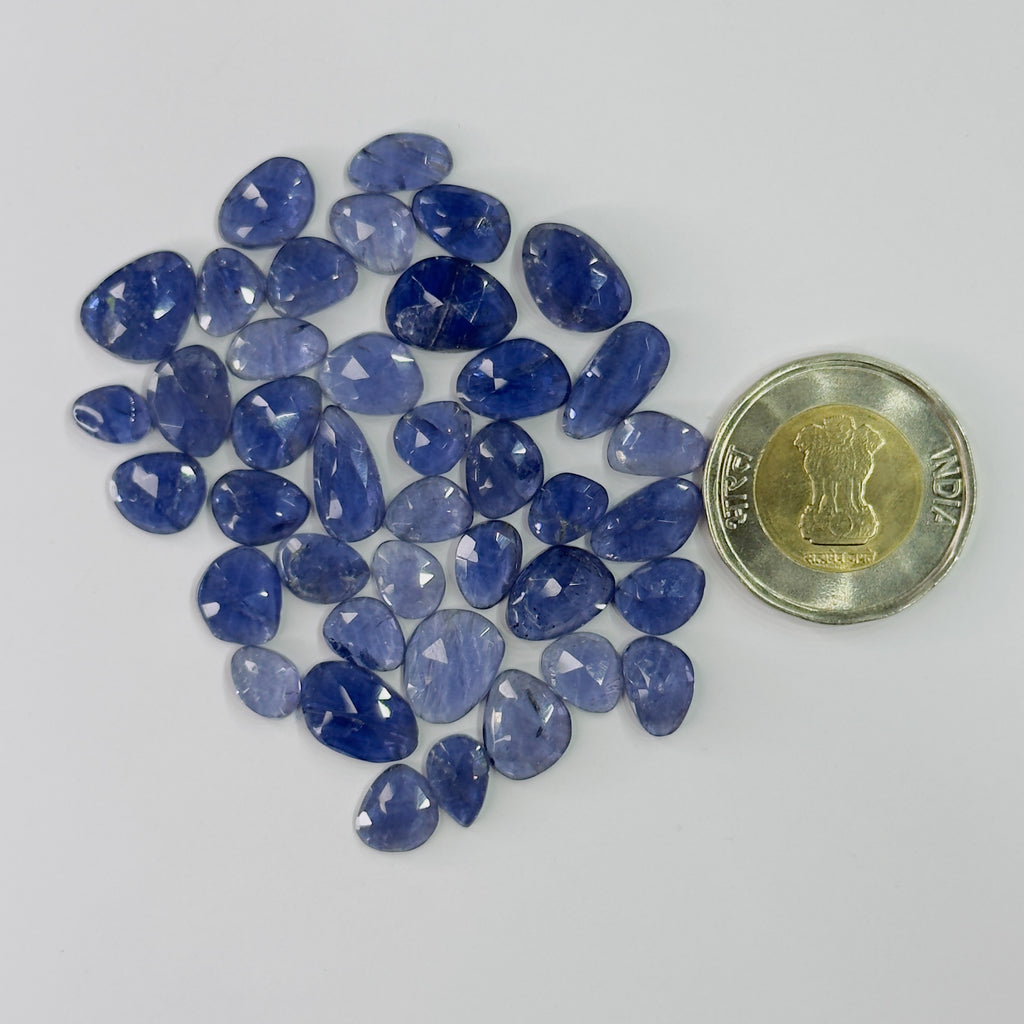 Blue gemstones with a coin for scale on a white background